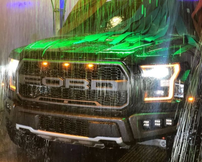 Ford Raptor under green-lit rinse water near the end of the tunnel