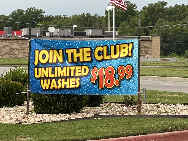 Join the Club banner advertising unlimited washes for $18.99 beside the road at Fast Wash Coweta