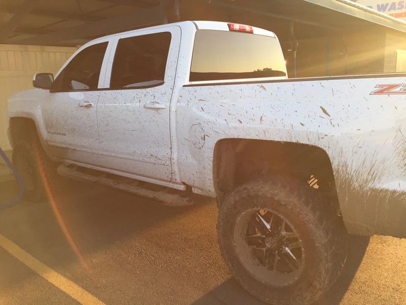 White Chevy Silverado splattered with red mud before its wash