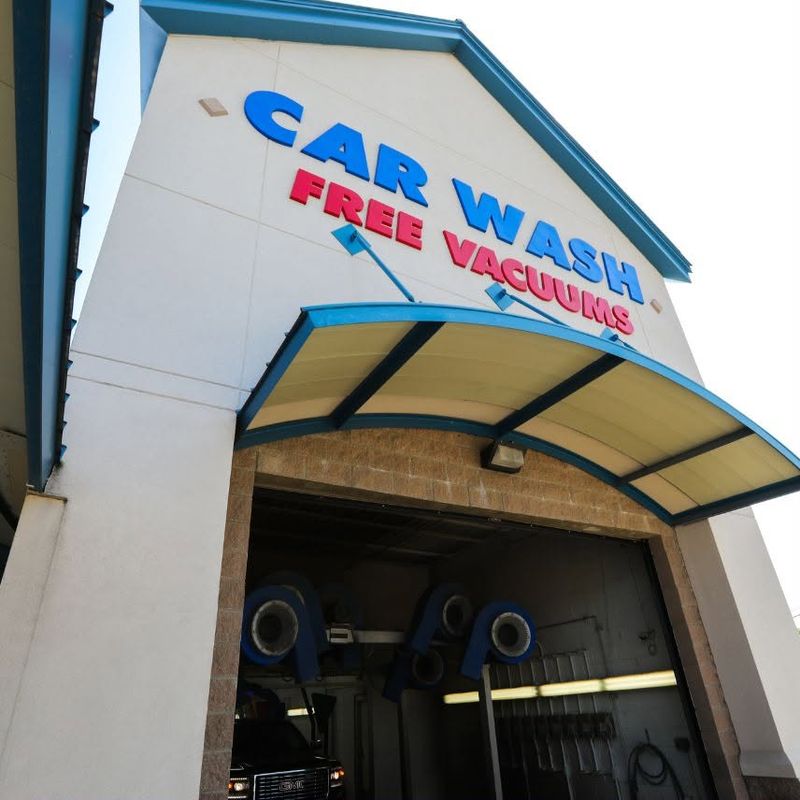 Fast Wash Coweta tunnel entrance with the CAR WASH and FREE VACUUMS sign above it