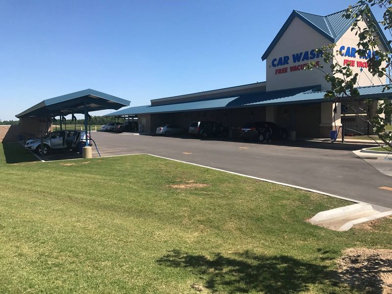 Covered vacuum lanes with cars beside the Fast Wash Coweta building